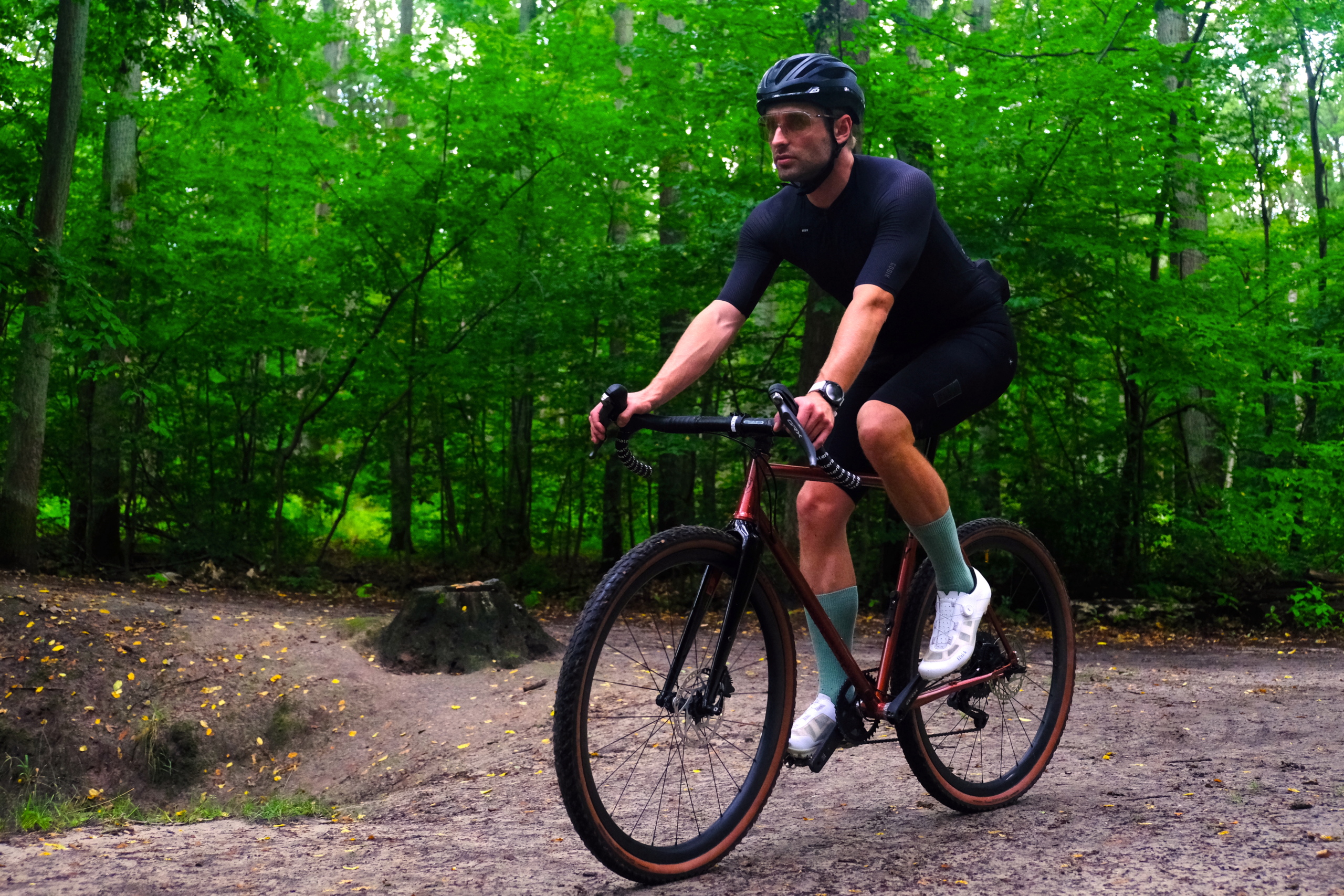 Kolarz jedzie na rowerze marki Antymateria typu gravel przez las